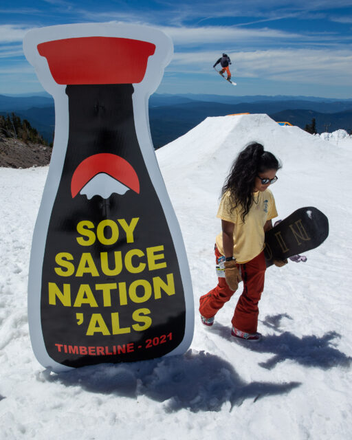Caleb Dhawornvej hits a hip on his snowboard behind a Soy Sauce Nation'als sign