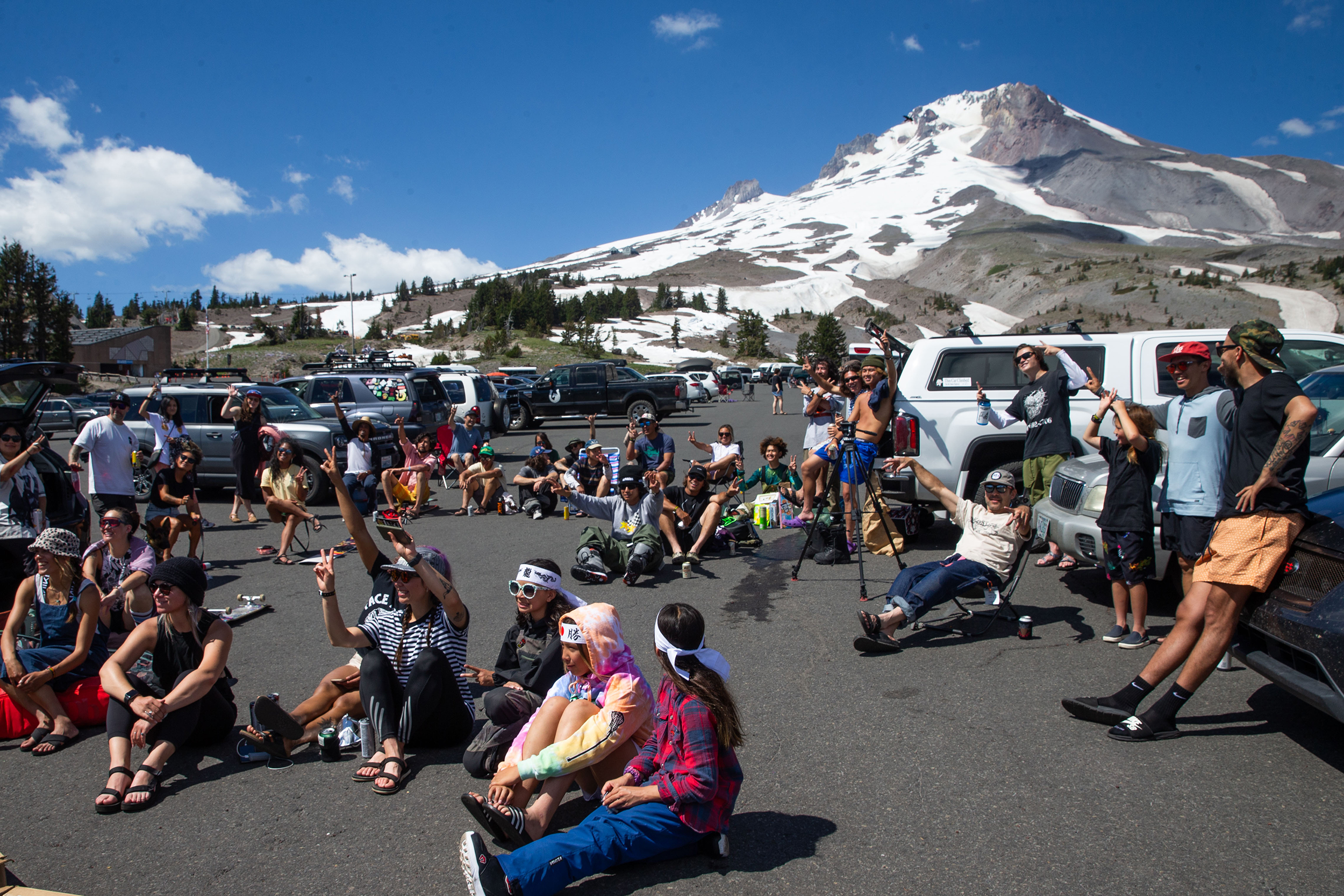 people hang out in a parking lot below Mount Hood