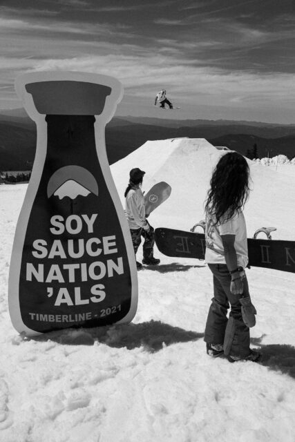 Steve Lauder snowboards in front of a Soy Sauce Nation'als sign