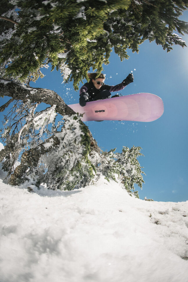 Maggie Leon snowboarding through the trees